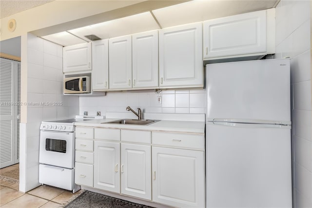 kitchen featuring light tile patterned floors, white appliances, a sink, white cabinets, and light countertops