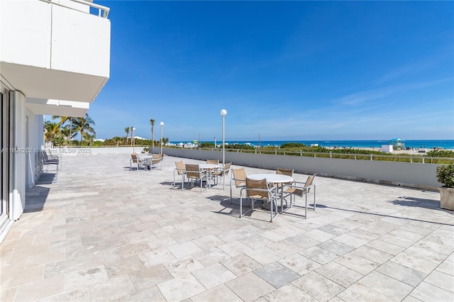 view of patio featuring outdoor dining area, a water view, and fence