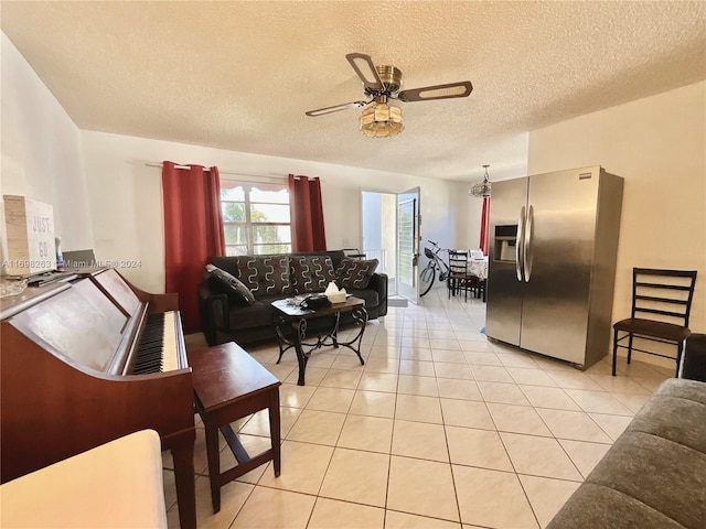 living room featuring ceiling fan, light tile patterned floors, and a textured ceiling