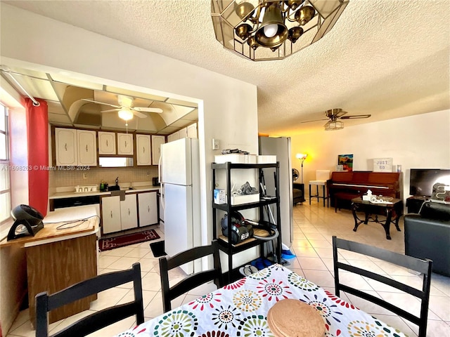 dining room featuring a textured ceiling, light tile patterned flooring, and ceiling fan with notable chandelier