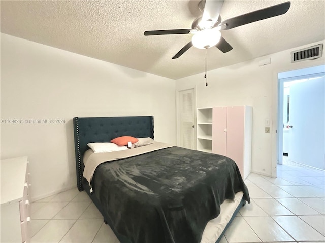 bedroom featuring a textured ceiling, ceiling fan, and light tile patterned flooring