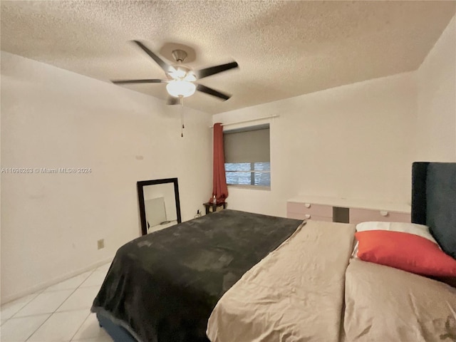 bedroom with ceiling fan, light tile patterned flooring, and a textured ceiling