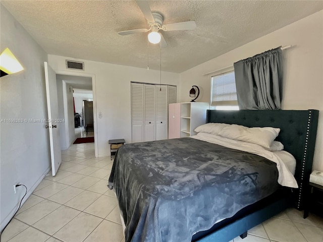 tiled bedroom with a textured ceiling, a closet, and ceiling fan