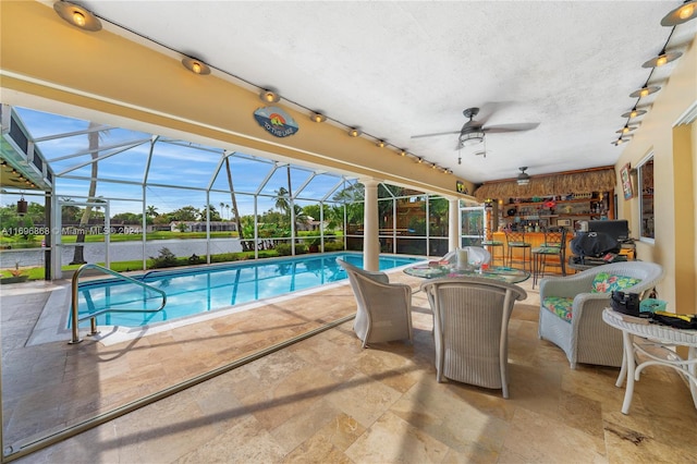 view of pool featuring glass enclosure, a water view, and a patio