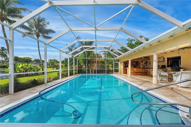 view of swimming pool with glass enclosure, ceiling fan, and a patio