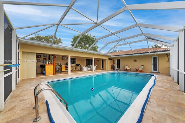 view of pool with an outdoor bar, a patio area, and a lanai