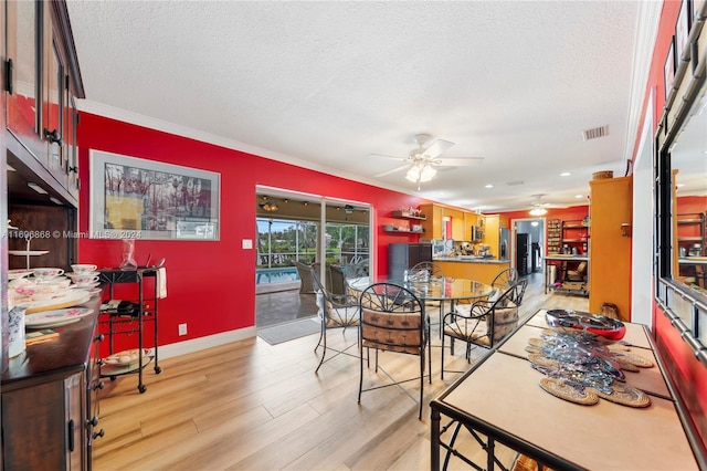 dining room with ceiling fan, crown molding, a textured ceiling, and light wood-type flooring