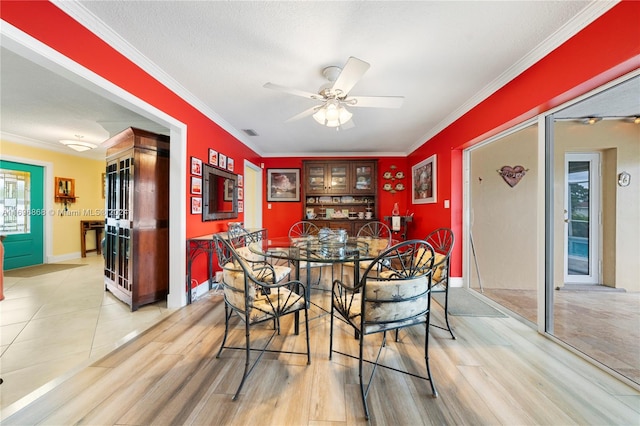 dining area featuring ceiling fan, light hardwood / wood-style flooring, a textured ceiling, and ornamental molding