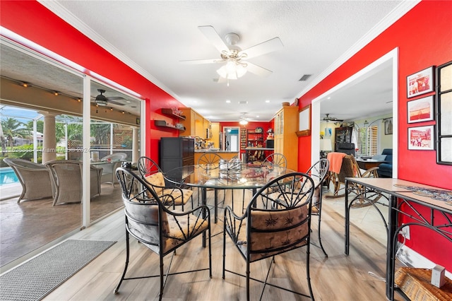 dining room with a textured ceiling, light wood-type flooring, and crown molding