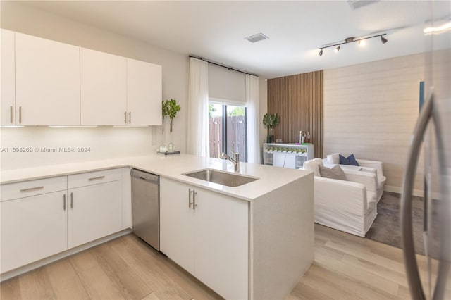 kitchen featuring sink, stainless steel dishwasher, kitchen peninsula, white cabinets, and light wood-type flooring