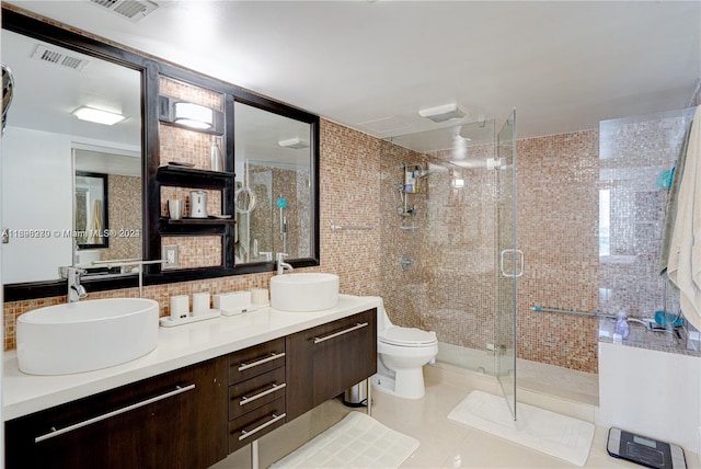 bathroom featuring toilet, vanity, tile patterned floors, and a shower with door