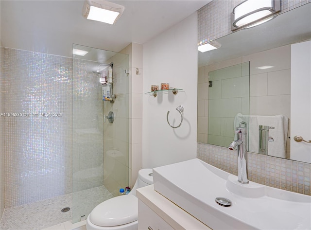 bathroom featuring decorative backsplash, a tile shower, vanity, and toilet