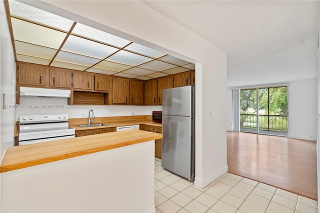 kitchen featuring butcher block countertops, light wood-type flooring, white appliances, and sink