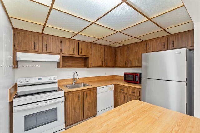 kitchen featuring sink, a drop ceiling, and white appliances