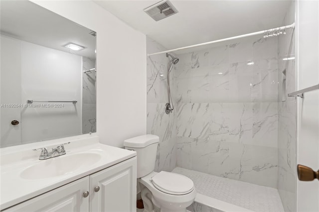 bathroom with vanity, toilet, and a tile shower