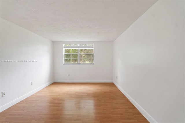 empty room featuring a textured ceiling and light hardwood / wood-style floors