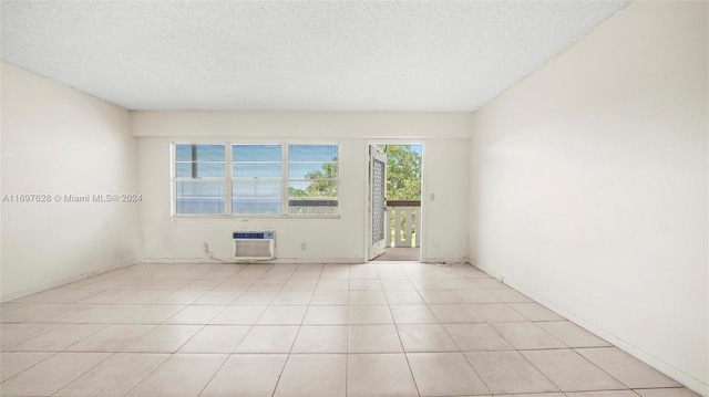 tiled empty room with a textured ceiling and a wall mounted AC