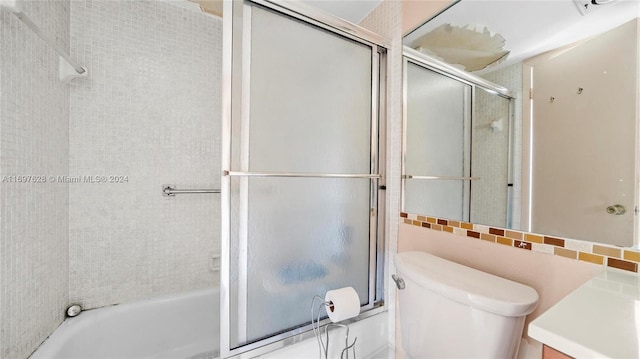 full bathroom with vanity, toilet, enclosed tub / shower combo, and tile walls