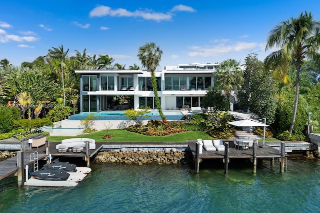 back of property with a water view, a sunroom, a patio area, and an outdoor pool