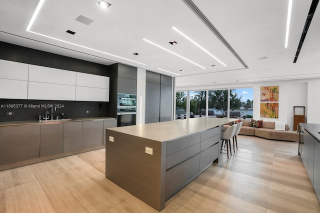 kitchen featuring tasteful backsplash, gray cabinetry, sink, white cabinets, and a large island