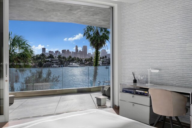 bedroom featuring a water view, light hardwood / wood-style flooring, and expansive windows