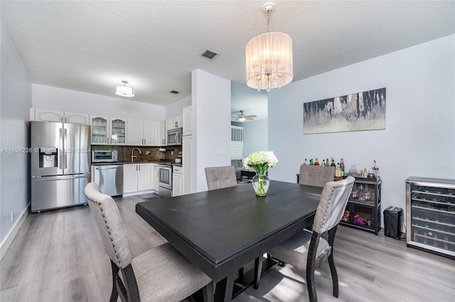 dining room featuring ceiling fan, light hardwood / wood-style flooring, beverage cooler, and sink