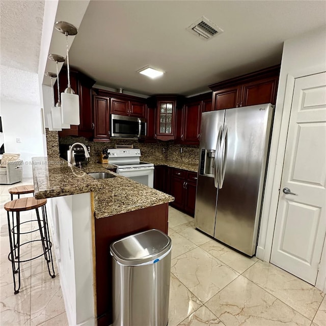 kitchen with sink, stainless steel appliances, tasteful backsplash, kitchen peninsula, and a breakfast bar area