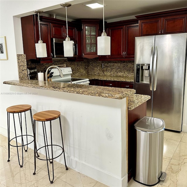 kitchen featuring stainless steel appliances, backsplash, kitchen peninsula, dark stone countertops, and pendant lighting