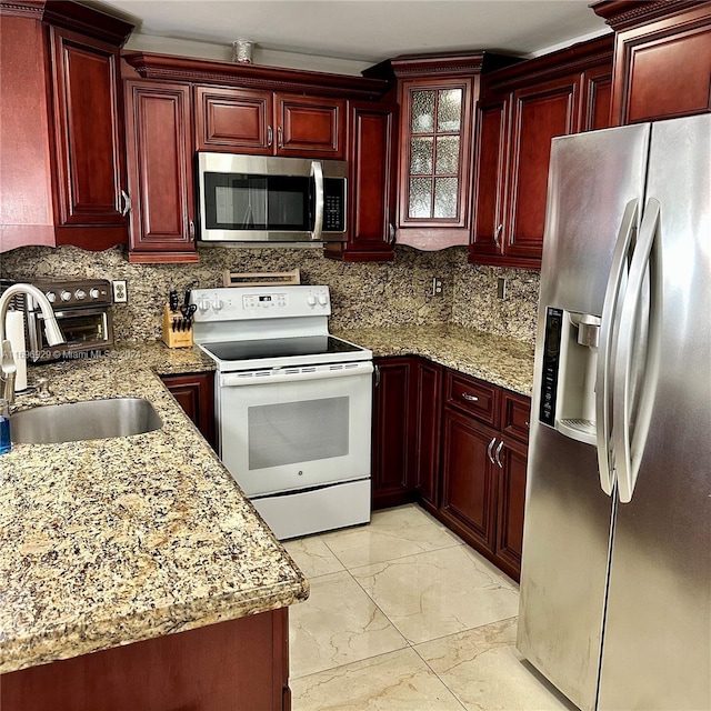 kitchen featuring tasteful backsplash, light stone countertops, sink, and stainless steel appliances