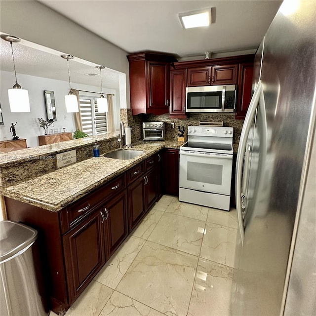 kitchen featuring kitchen peninsula, appliances with stainless steel finishes, decorative light fixtures, and sink