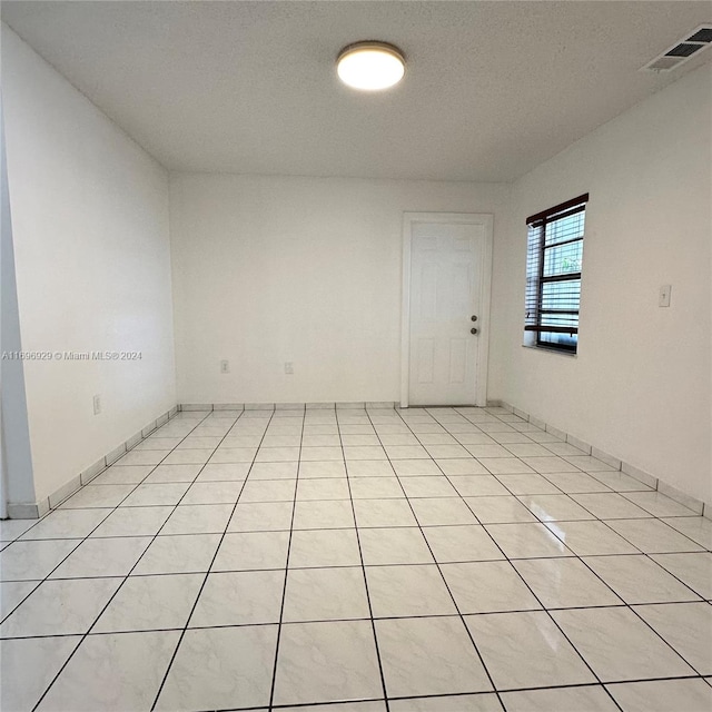 unfurnished room with light tile patterned floors and a textured ceiling