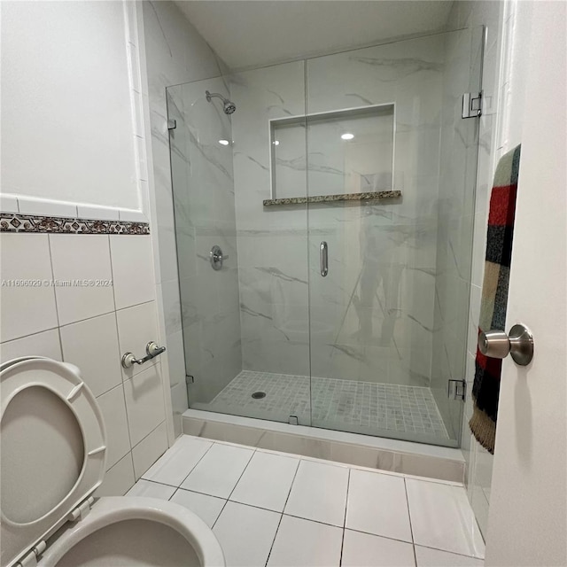 bathroom featuring tile patterned flooring, toilet, tile walls, and a shower with shower door