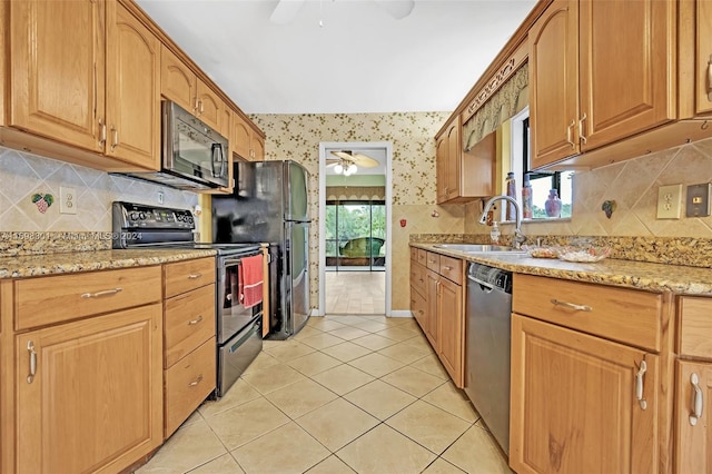 kitchen with light stone countertops, sink, decorative backsplash, light tile patterned floors, and appliances with stainless steel finishes