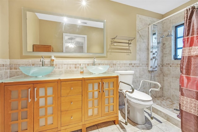 bathroom with vanity, tile patterned flooring, toilet, tiled shower, and tile walls