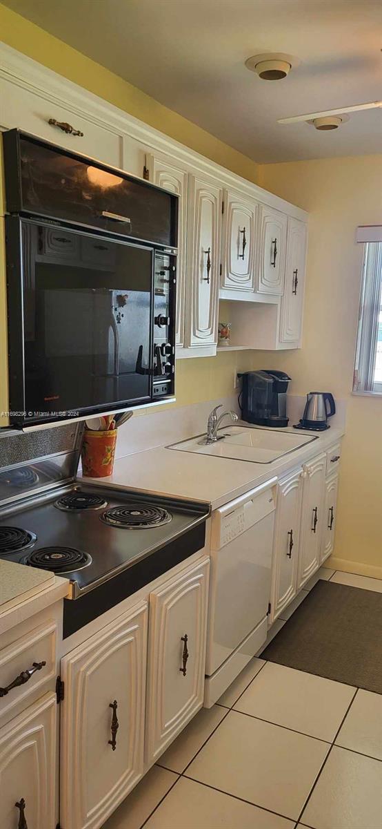 kitchen with tile patterned floors, white cabinetry, dishwasher, and sink