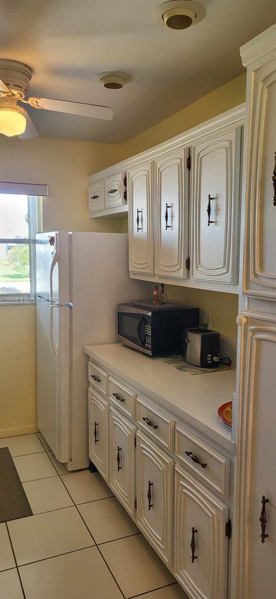 kitchen featuring light tile patterned floors, white cabinetry, and ceiling fan