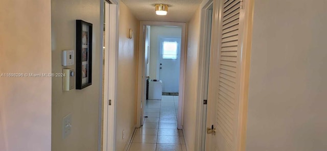 hall featuring light tile patterned floors and a textured ceiling