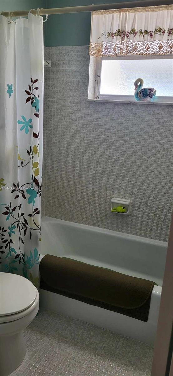 bathroom with toilet and shower / bath combo with shower curtain