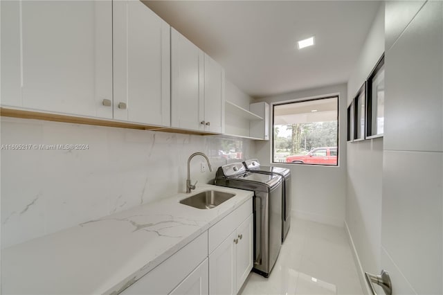 clothes washing area with sink, cabinets, and independent washer and dryer