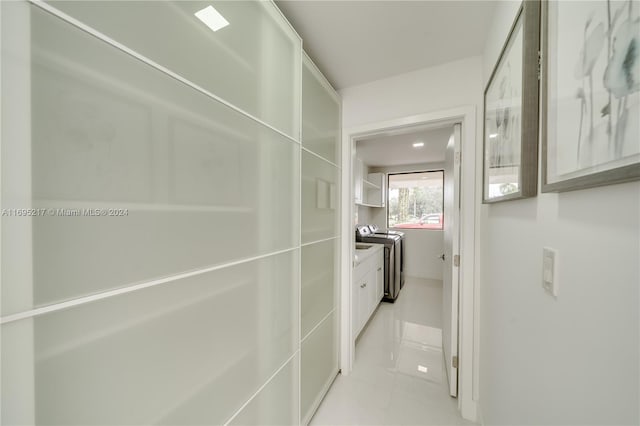 hallway with washer / dryer and light tile patterned floors