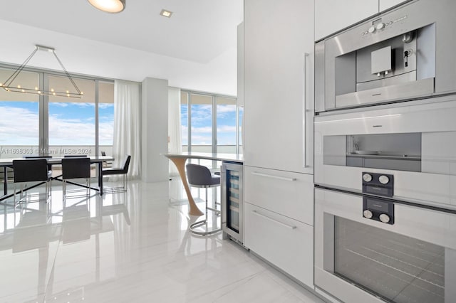 kitchen with hanging light fixtures, beverage cooler, double oven, a chandelier, and white cabinets