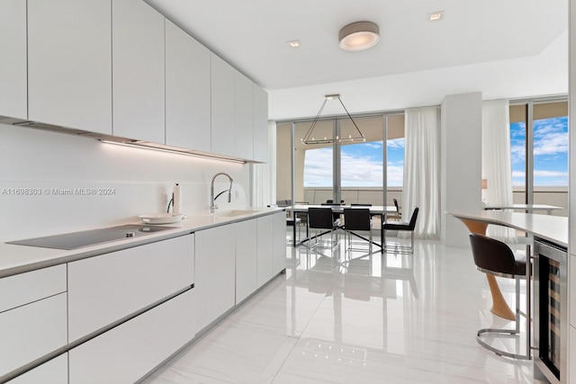 kitchen featuring pendant lighting, sink, wine cooler, black electric cooktop, and white cabinetry