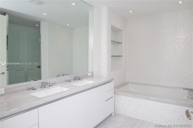 bathroom with vanity and tiled tub