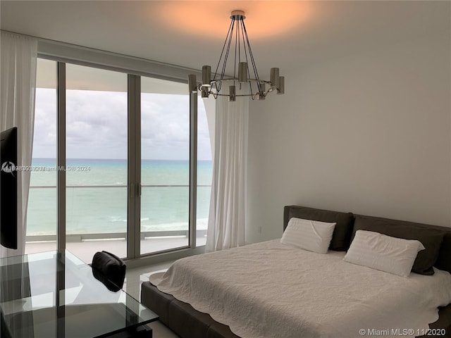 bedroom with multiple windows, a water view, and a notable chandelier