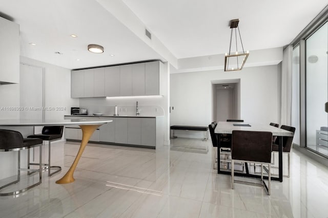 kitchen featuring a breakfast bar area, gray cabinets, a large island, and pendant lighting