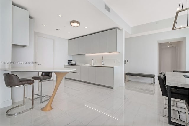 16901 Collins Ave Unit 1402, Sunny Isles Beach, FL 33160 - kitchen with modern cabinets, light countertops, a breakfast bar area, and light marble finish floors