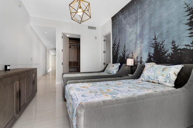 bedroom featuring a walk in closet, an inviting chandelier, and a closet