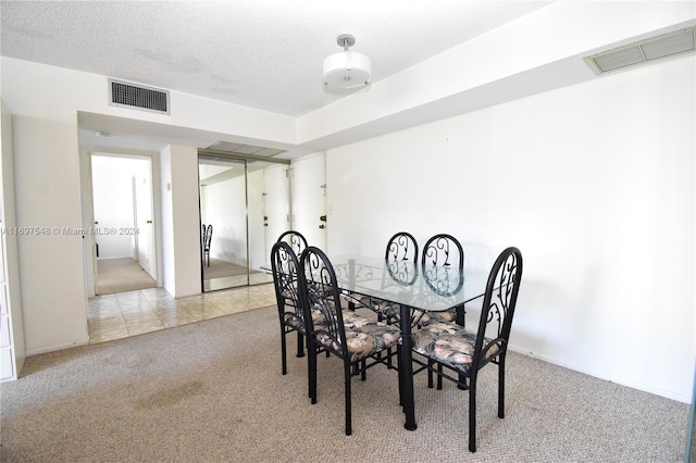 carpeted dining area with a textured ceiling