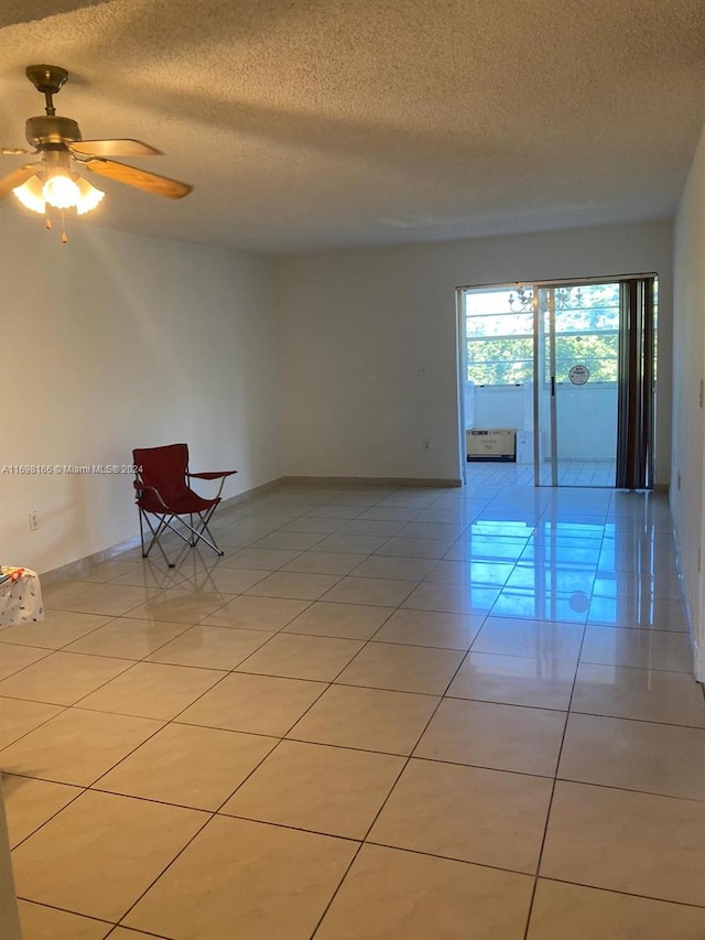 spare room with a textured ceiling, ceiling fan, and light tile patterned floors