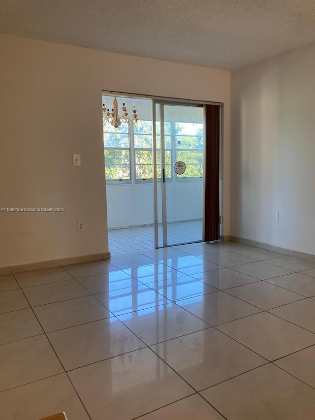 tiled empty room featuring a textured ceiling